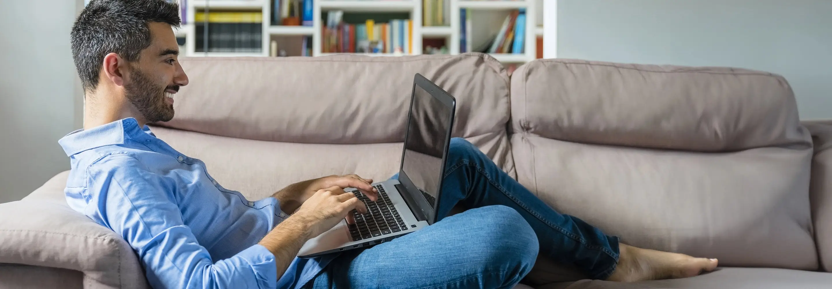 Uomo che lavora sul divano con il suo laptop